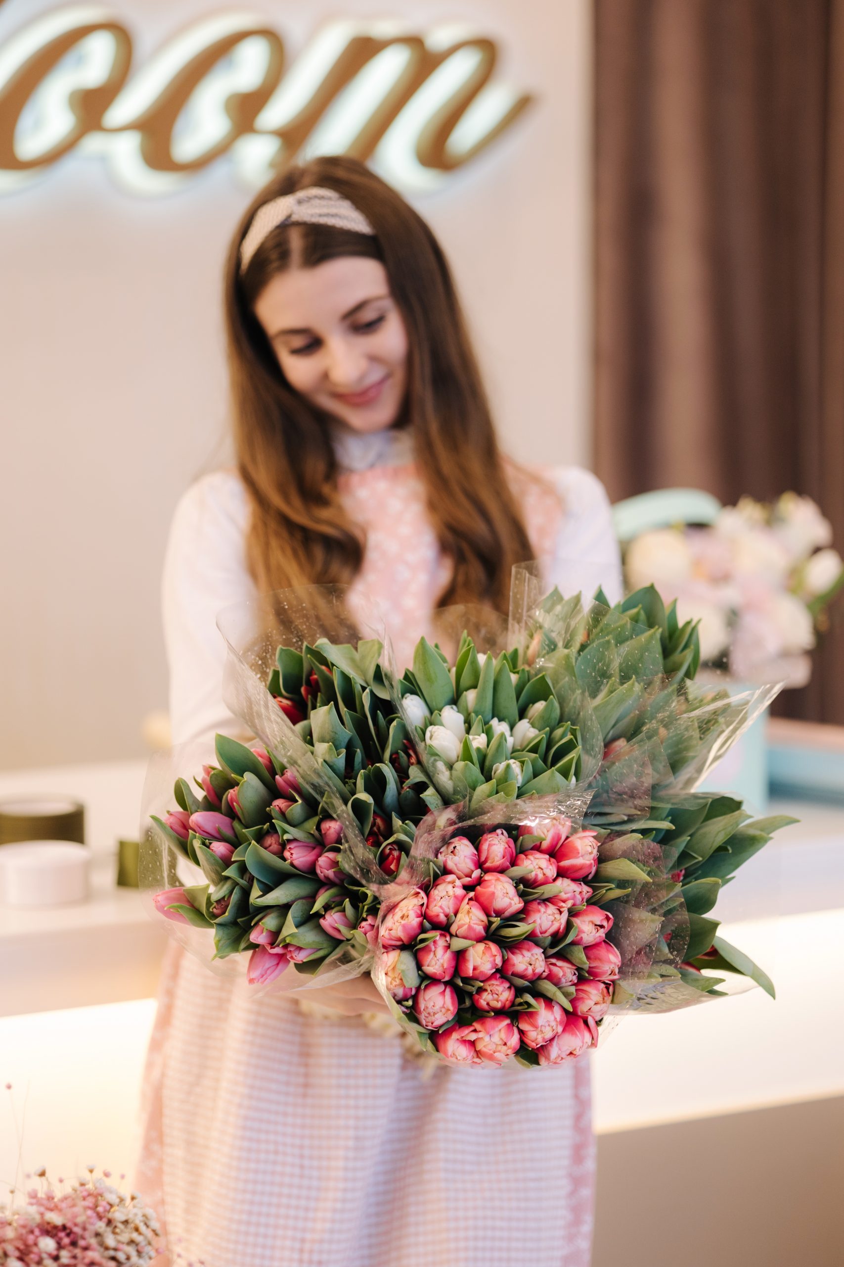 Woman make spring bouquet. Female florist wrapping beautiful bouquet of spring flowers in pack paper on the table. Beautiful flower composition