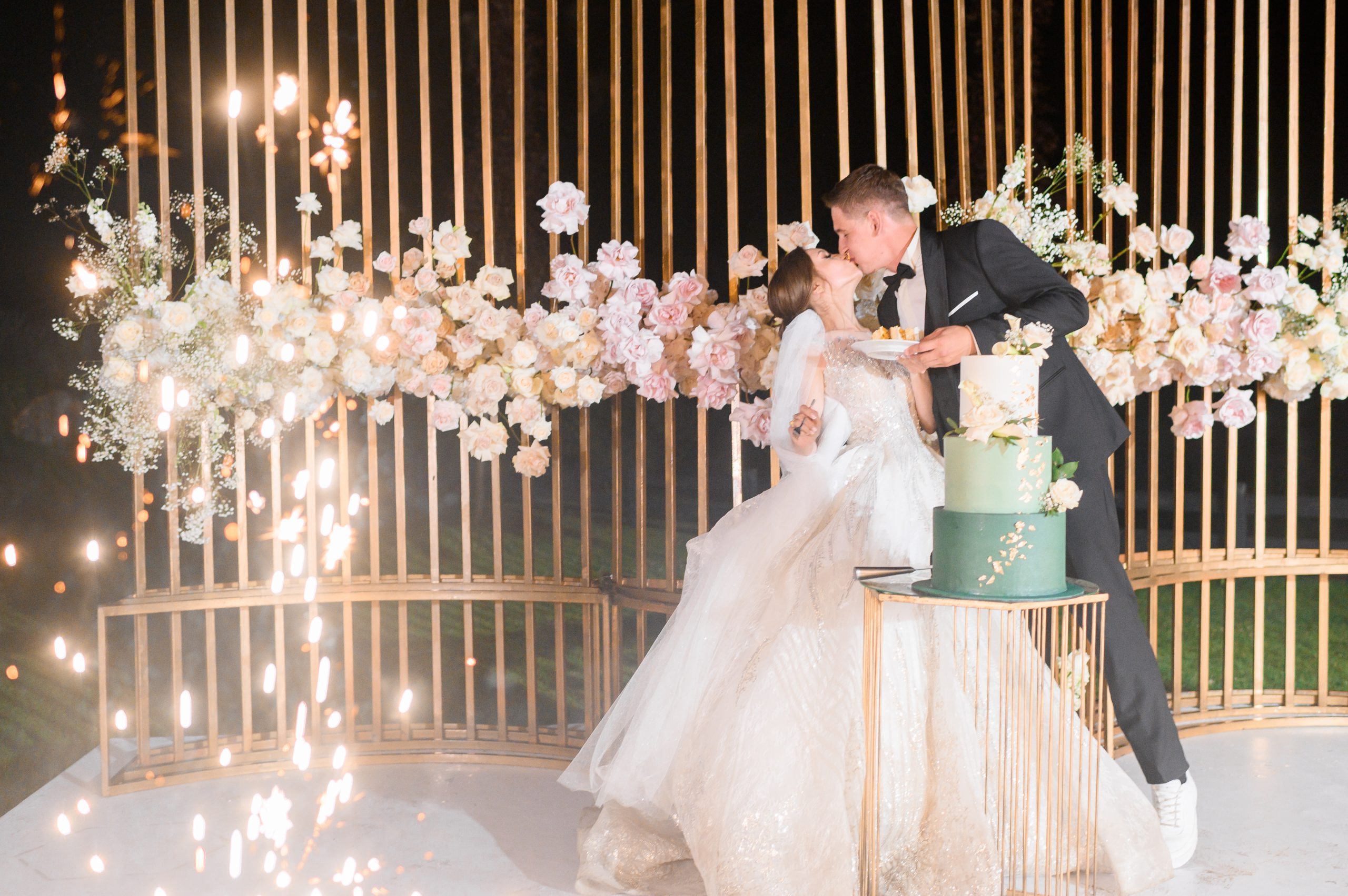 side-view-happy-bride-groom-which-eating-wedding-cake-kissing-each-other-while-standing-background-beautiful-wedding-arch-which-decorated-by-metal-roses-during-evening-ceremony